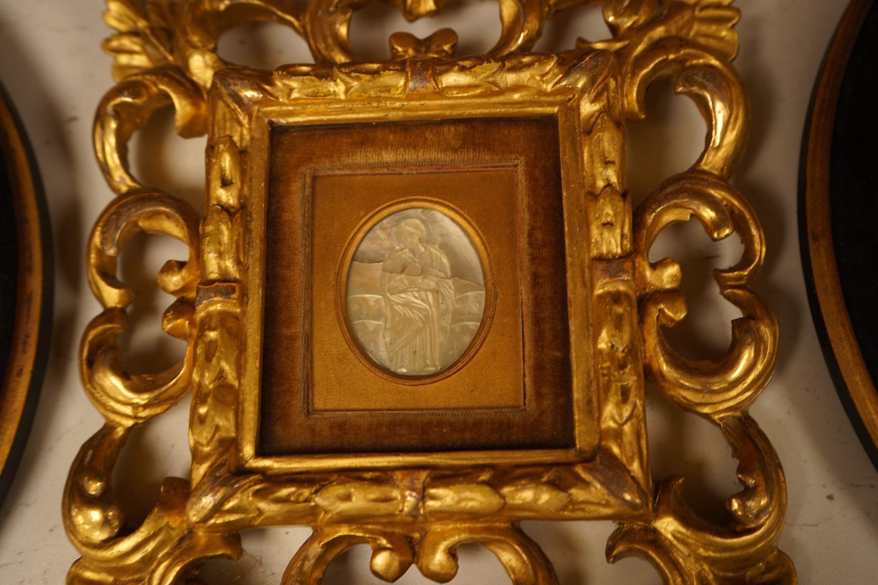 A late 19th century mother of pearl plaque of a saint, housed in a gilt wood florentine frame, together with a pair of Copenhagen biscuit porcelain plaques of Night and Day after Thorvaldsen, in convex frames